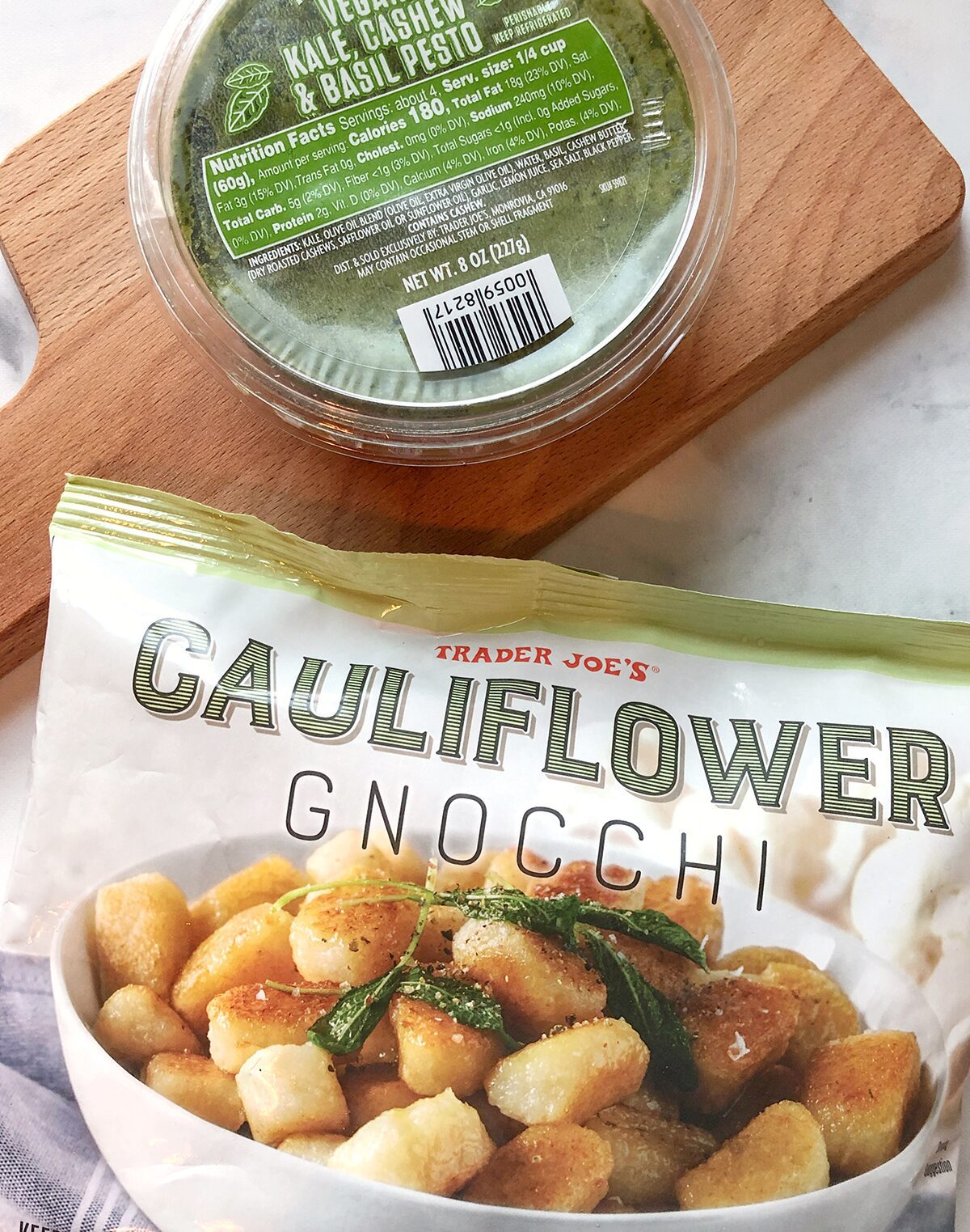 A package of Trader Joe's cauliflower gnocchi and a container of pesto.
