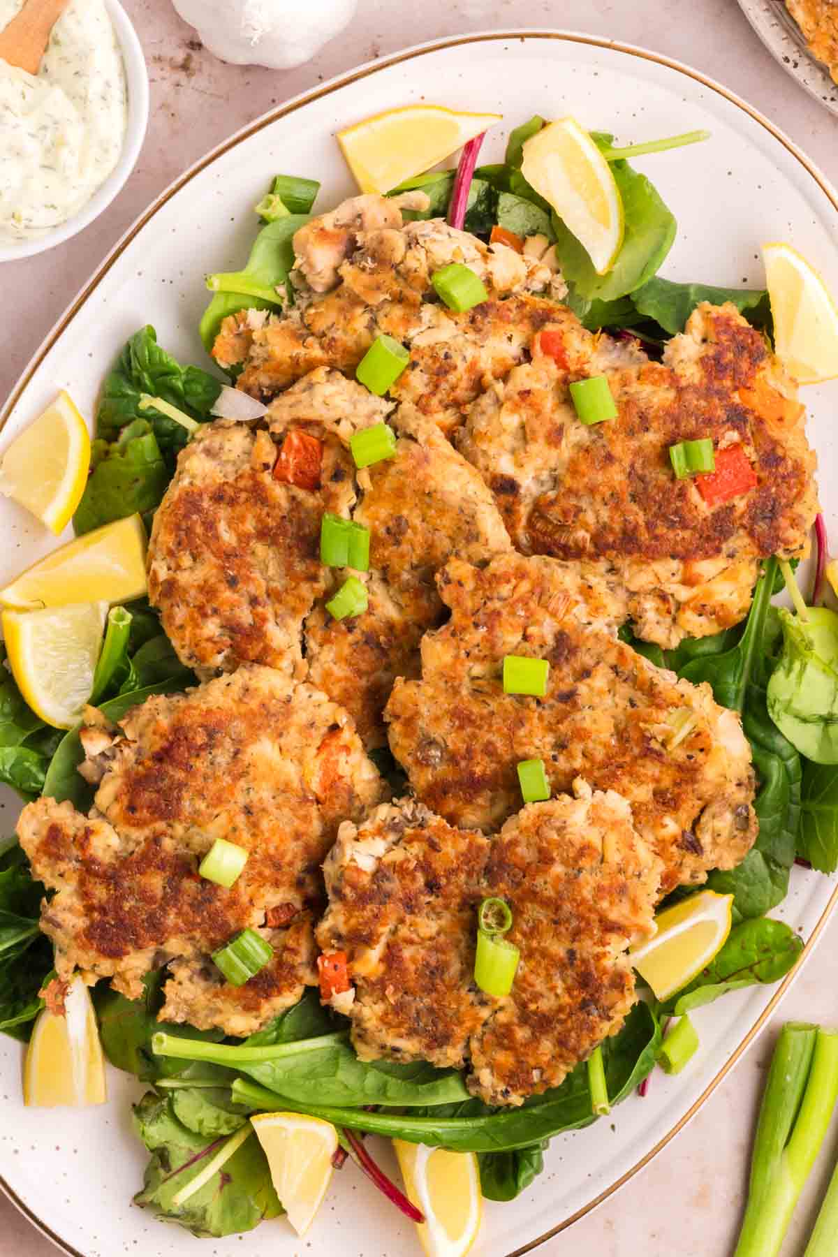 Salmon cakes on a serving tray with lemon wedges.