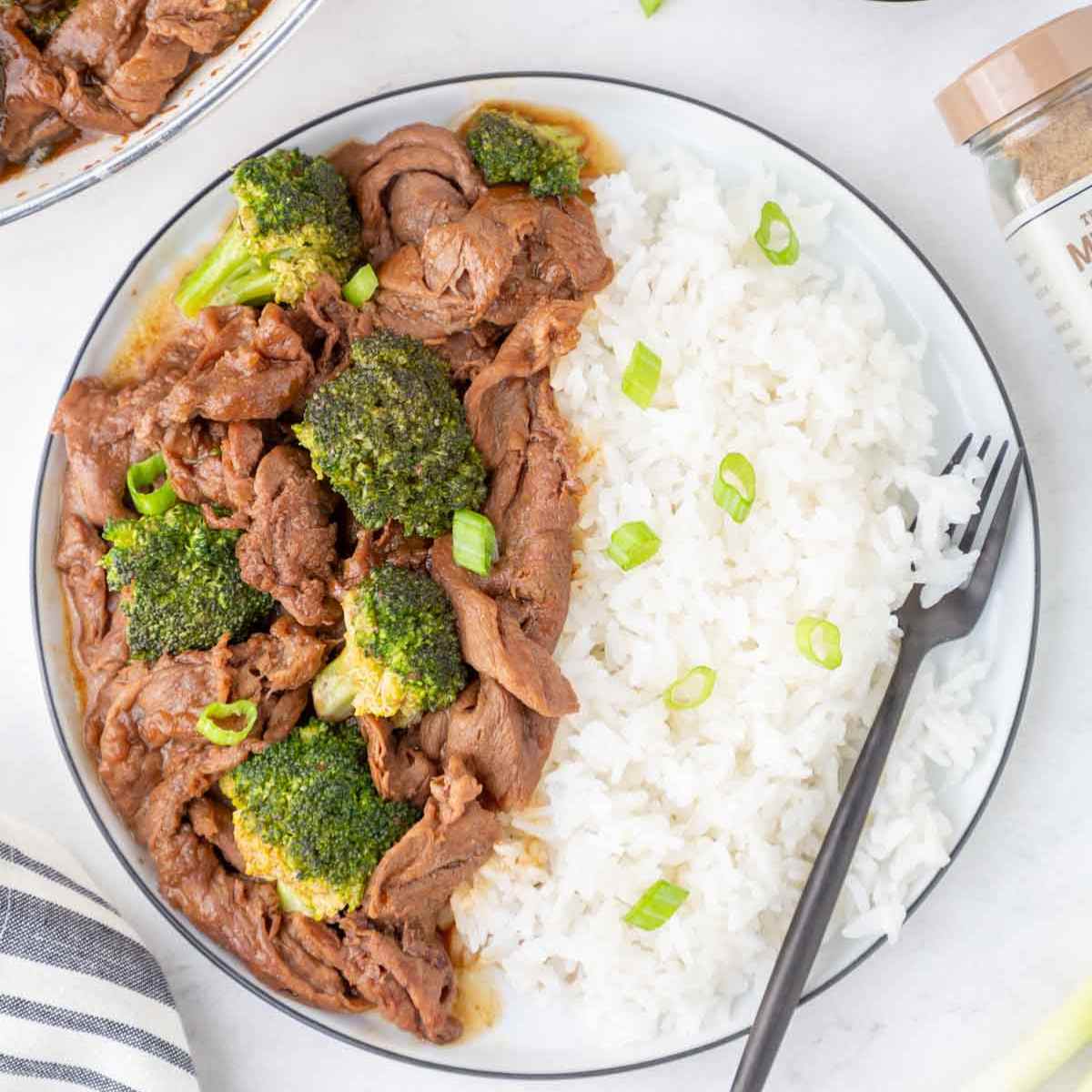 Trader Joe's broccoli beef made with shaved steak on a plate with rice and a fork.