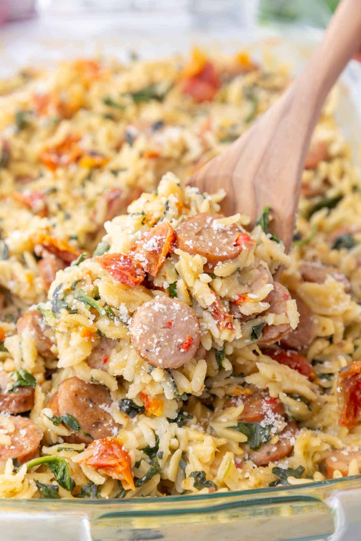 Close up of Trader Joe's sausage and orzo bake on a wooden spoon.