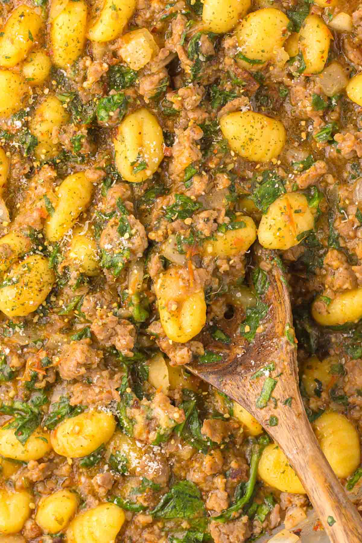 detailed photo of Trader Joe's sausage and spinach gnocchi on a wooden spoon.