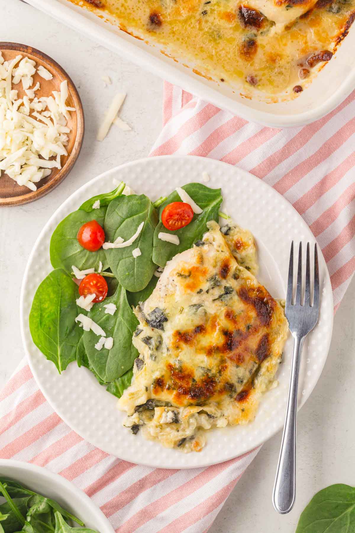 Trader Joe's spinach and artichoke chicken on a plate with salad.