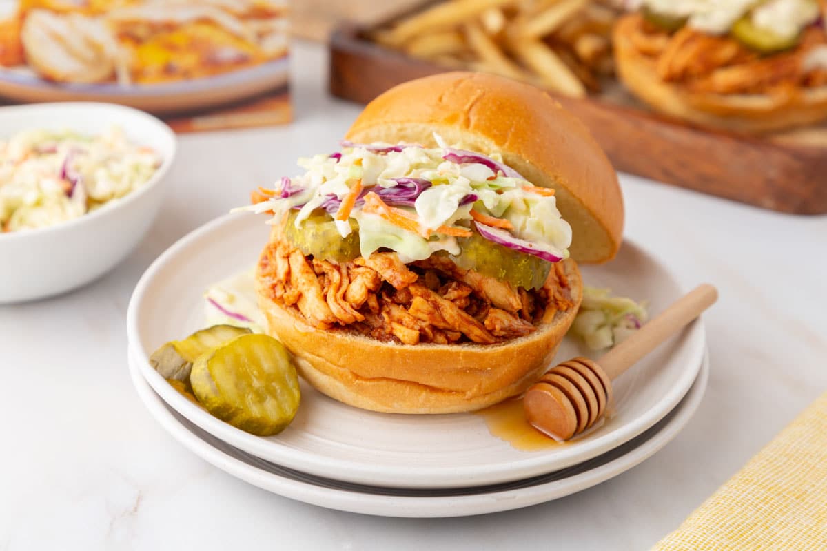 Trader Joe's pulled chicken sandwich on plate with slaw and pickles.