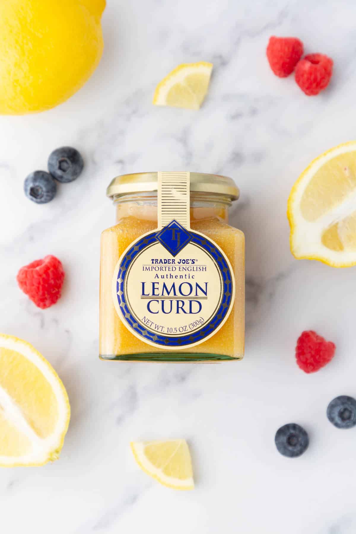 A jar of Trader Joe's lemon curd surrounded by berries.